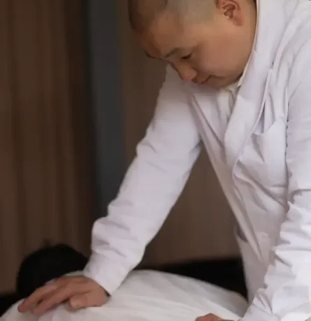 a man in a white coat is giving a person a chinese remedial massage (tuina)