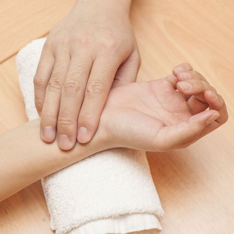 a person taking someone 's pulse with their hands