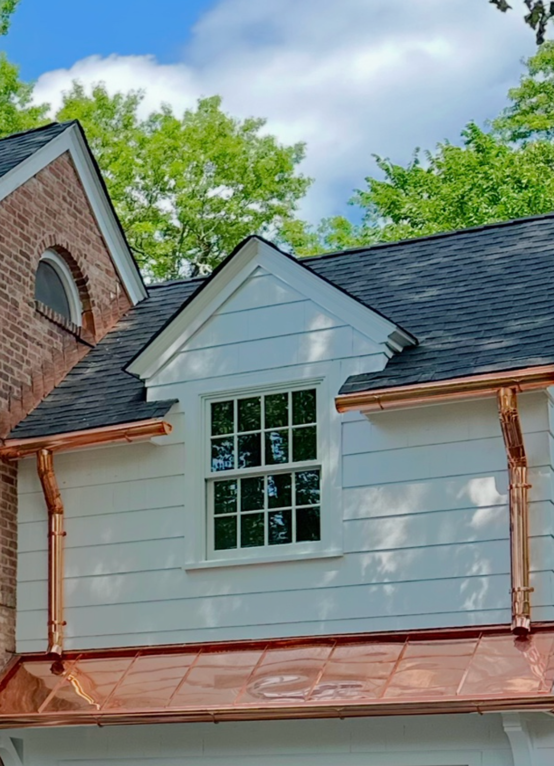 A white house with a black roof and copper gutters