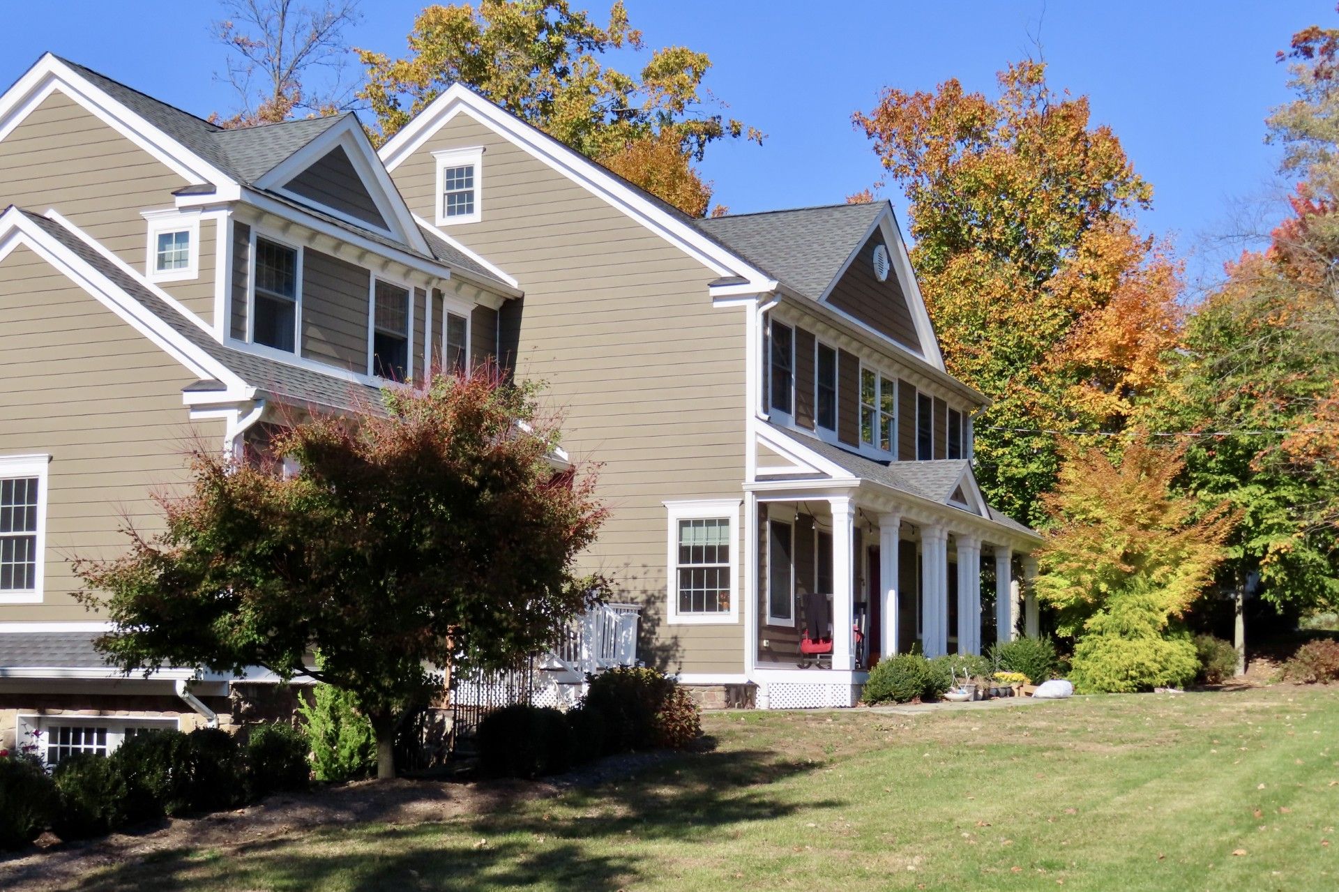A large house with a large porch is surrounded by trees