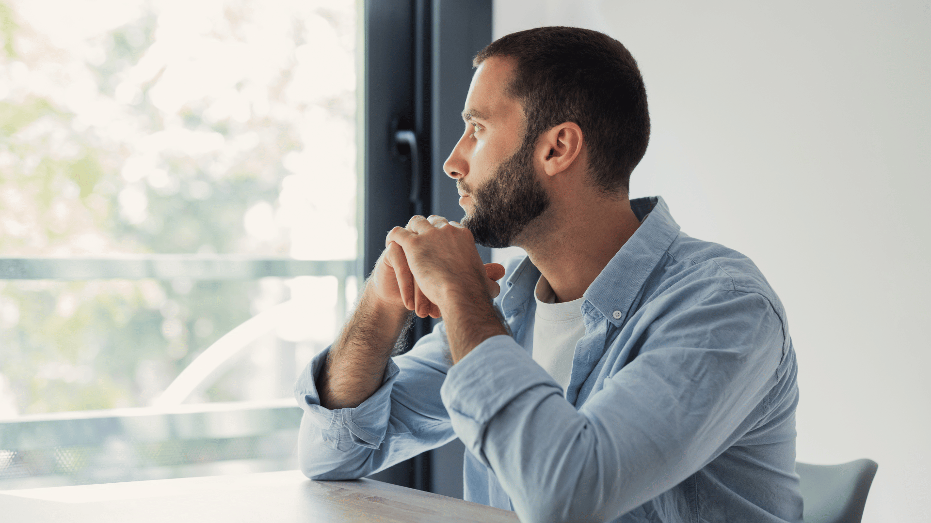 Adult adoptee reflecting near a window while processing adoption identity and trauma.