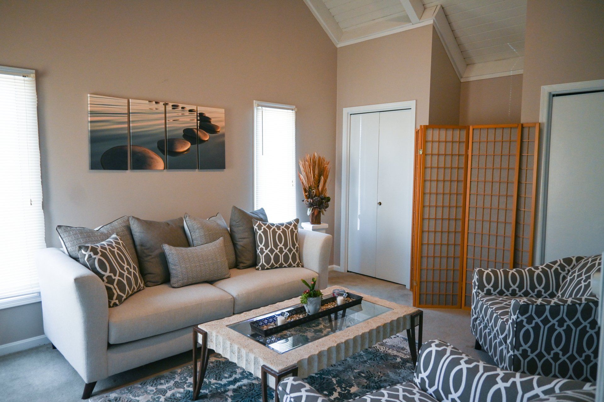 A living room with a couch , chair , coffee table and painting on the wall.