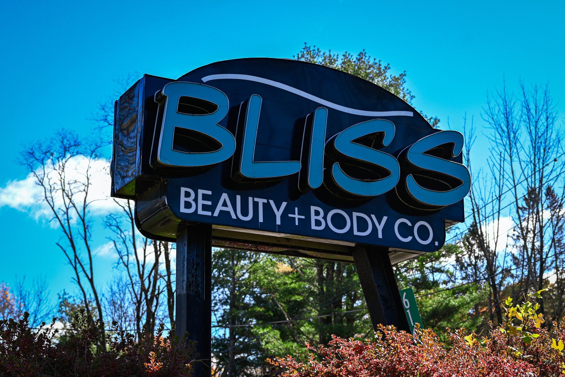 A bliss beauty and body co. sign with trees in the background