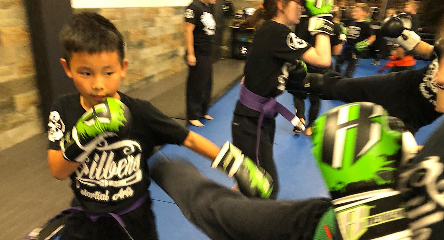 a group of children are practicing martial arts in a gym .