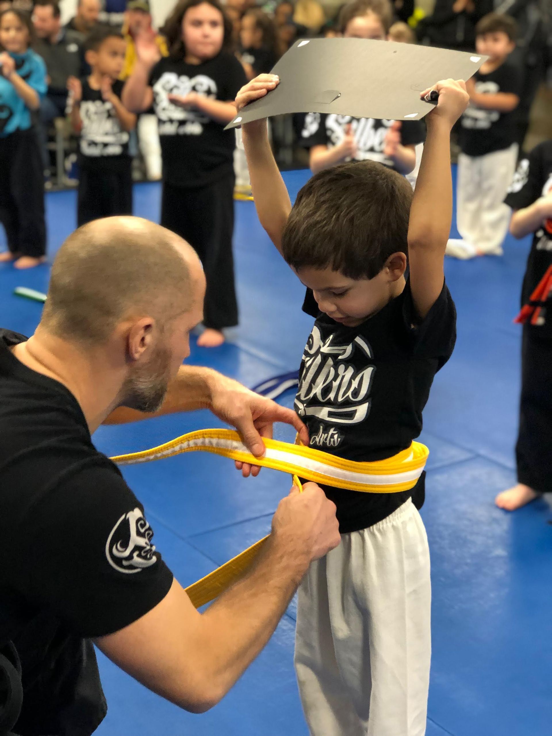 a man is helping a young boy with his belt