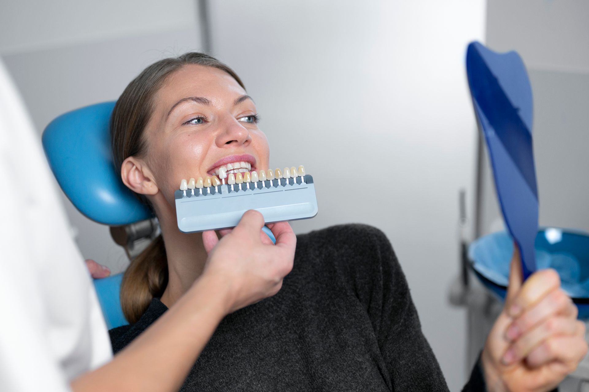 Doctor showing dental implant to female patient at dentist's office.