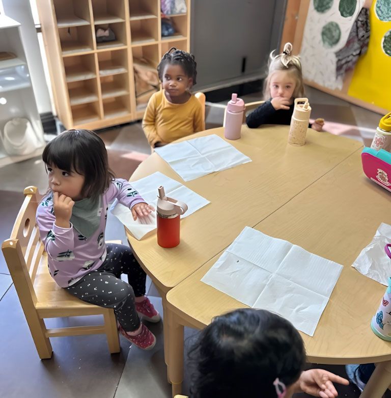 Toddlers sitting at a table in a Montessori classroom.