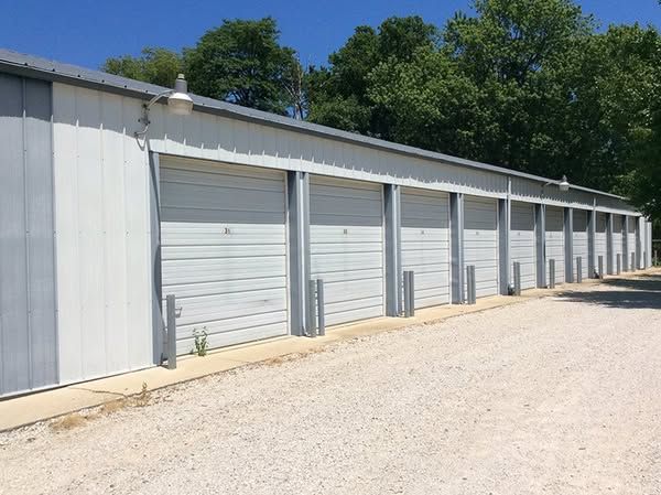 A row of garage doors are lined up next to each other on a gravel road.