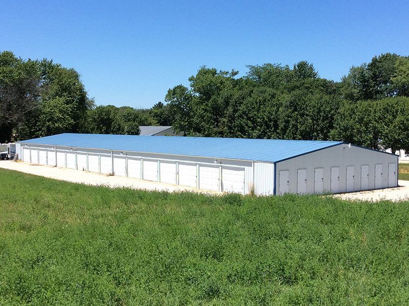 A large building with a blue roof is in the middle of a grassy field