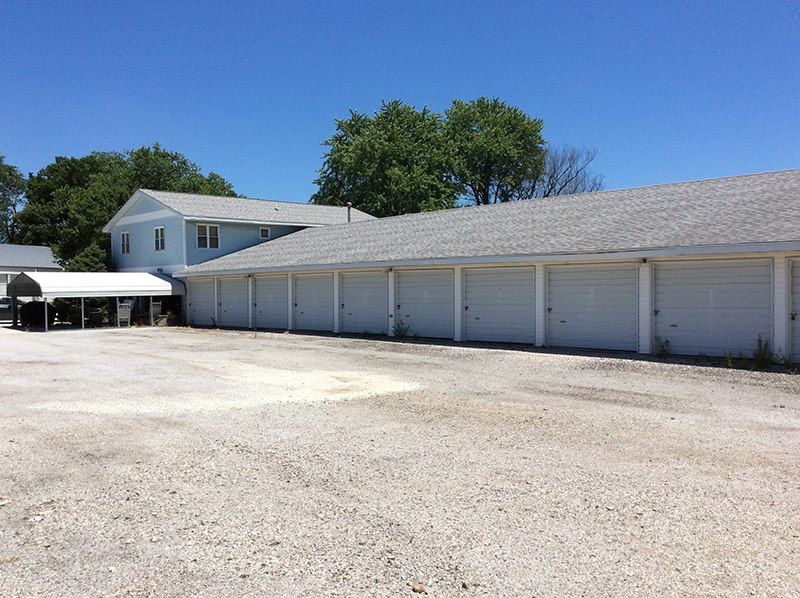 A row of white garage doors are lined up in front of a building.