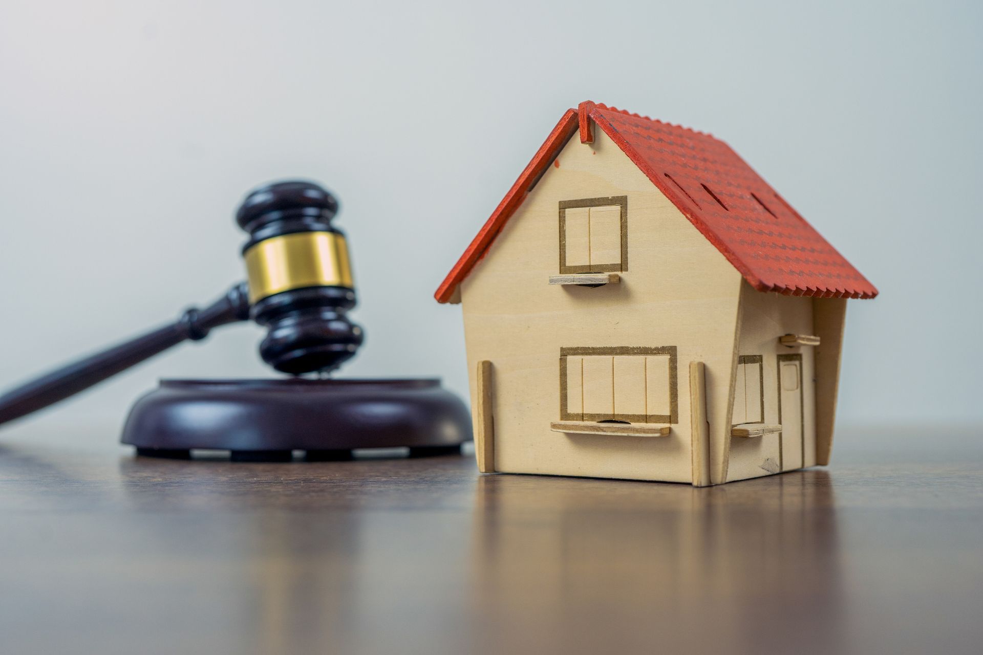 A gavel with a model house next to it on a table.