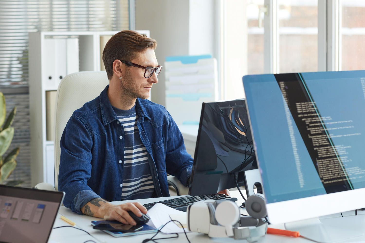 Mitarbeiter überwacht IT Wartung und Systemstatus an mehreren Bildschirmen im Büro.