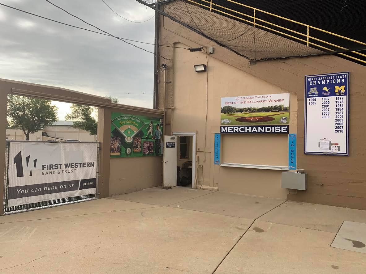 Outdoor concession stand with service window, menu board, and signs under a covered walkway