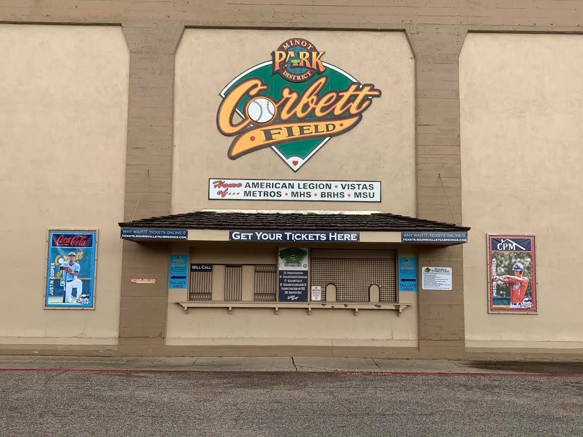 Closed Corbett Theatre ticket booth and beige exterior wall with colorful signs and posters