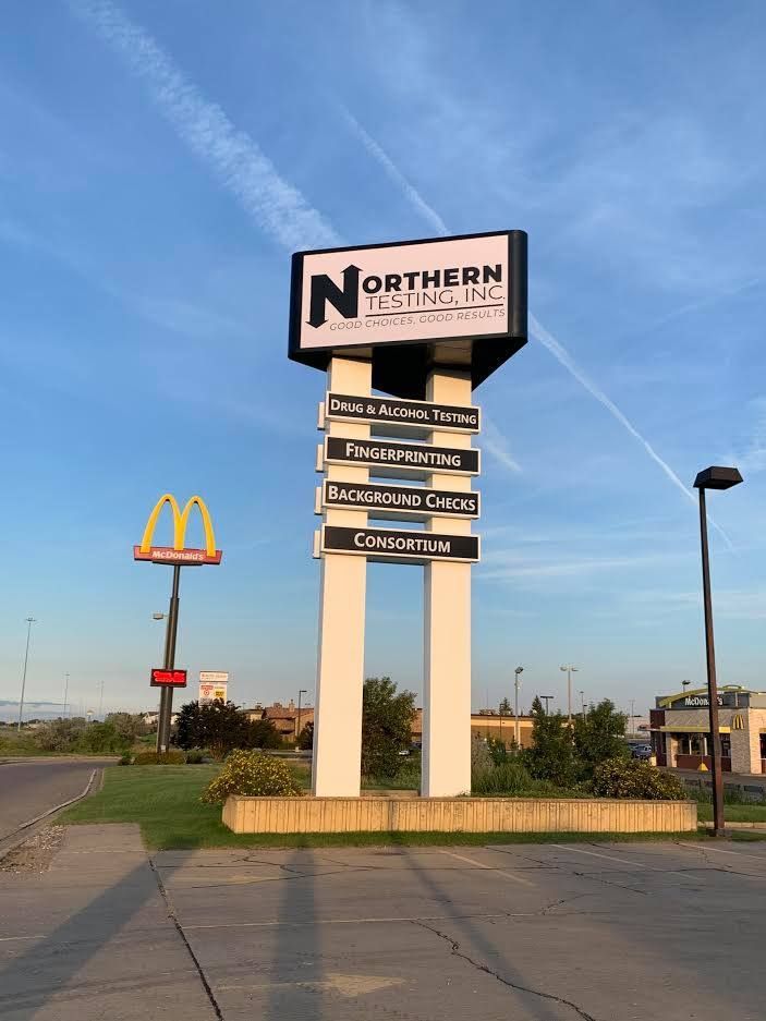 Northern billboard sign beside a McDonald’s logo on a roadside under a blue sky.