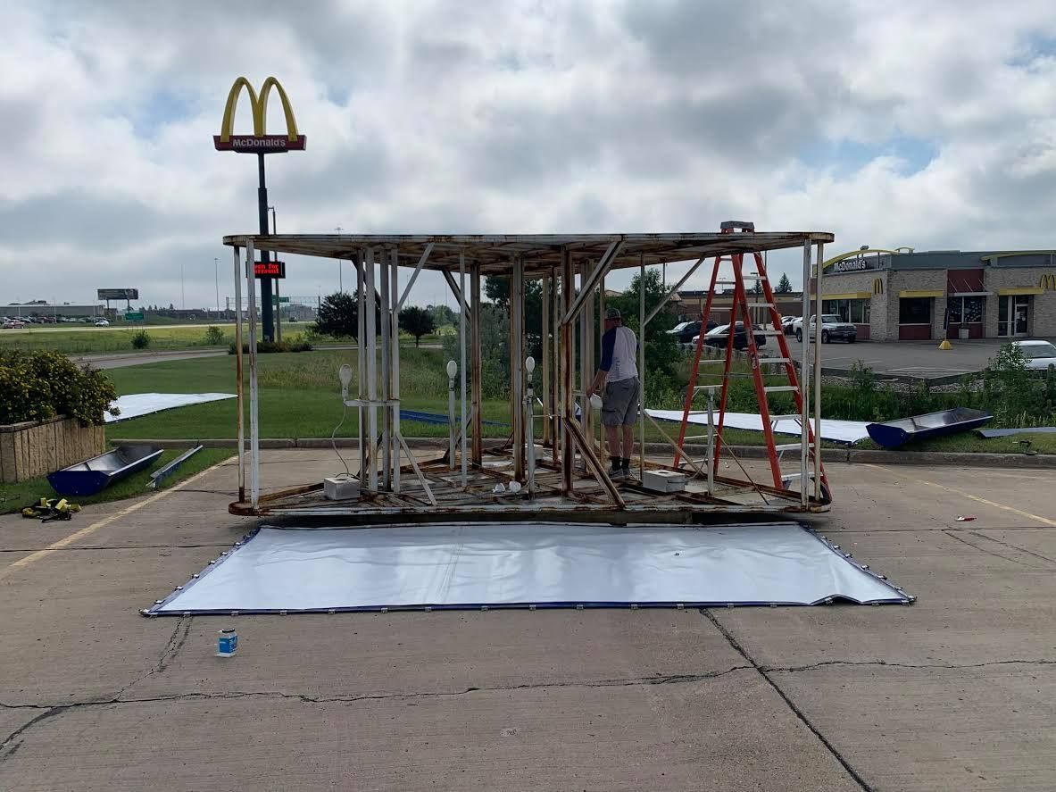 Collapsed playground structure on concrete pad with a McDonald’s sign in the background under cloudy skies