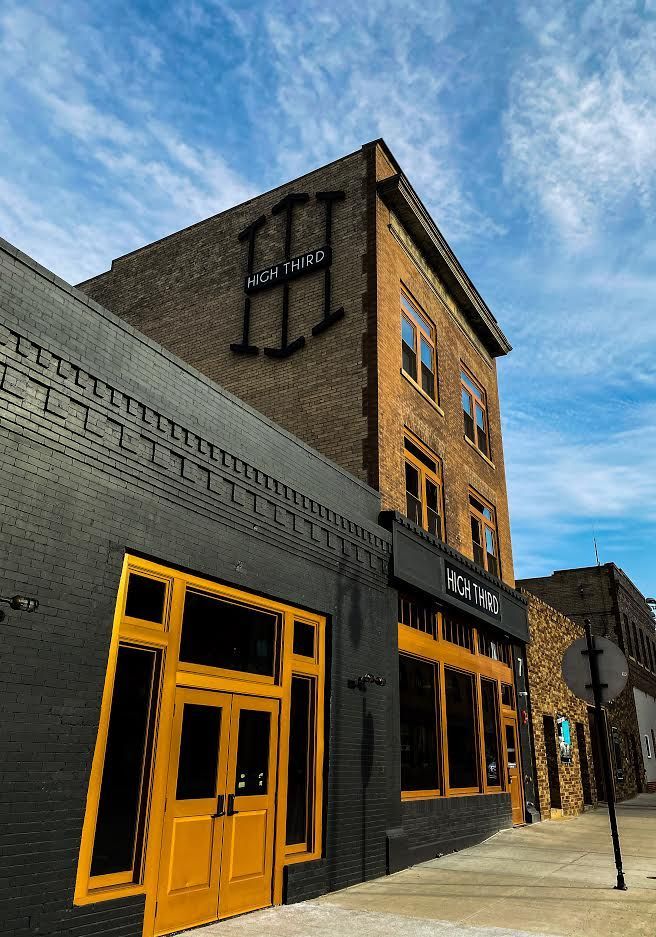 Corner brick building with black and yellow storefront trim under a blue sky