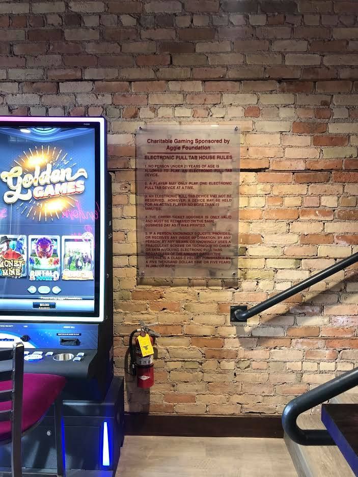 Brick wall with a tribute plaque, arcade game screen on the left, and a handrail on the right.