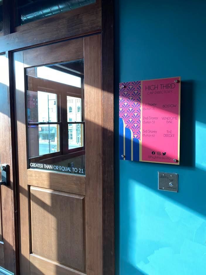 Wooden door beside blue wall with pink notice and small window