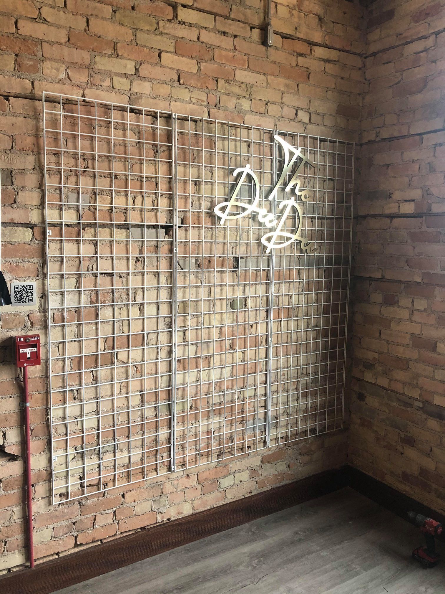 Brick wall with metal grid panels and white graffiti in a corner