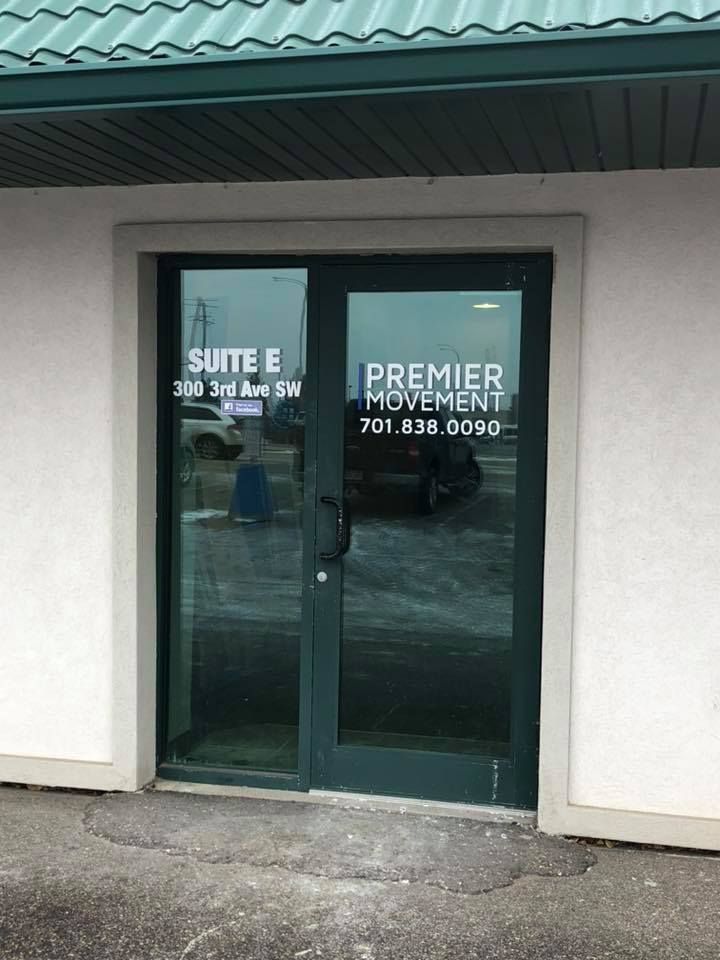 Glass storefront doors labeled “Premier Movement” and “Suite E” with an address and phone number.