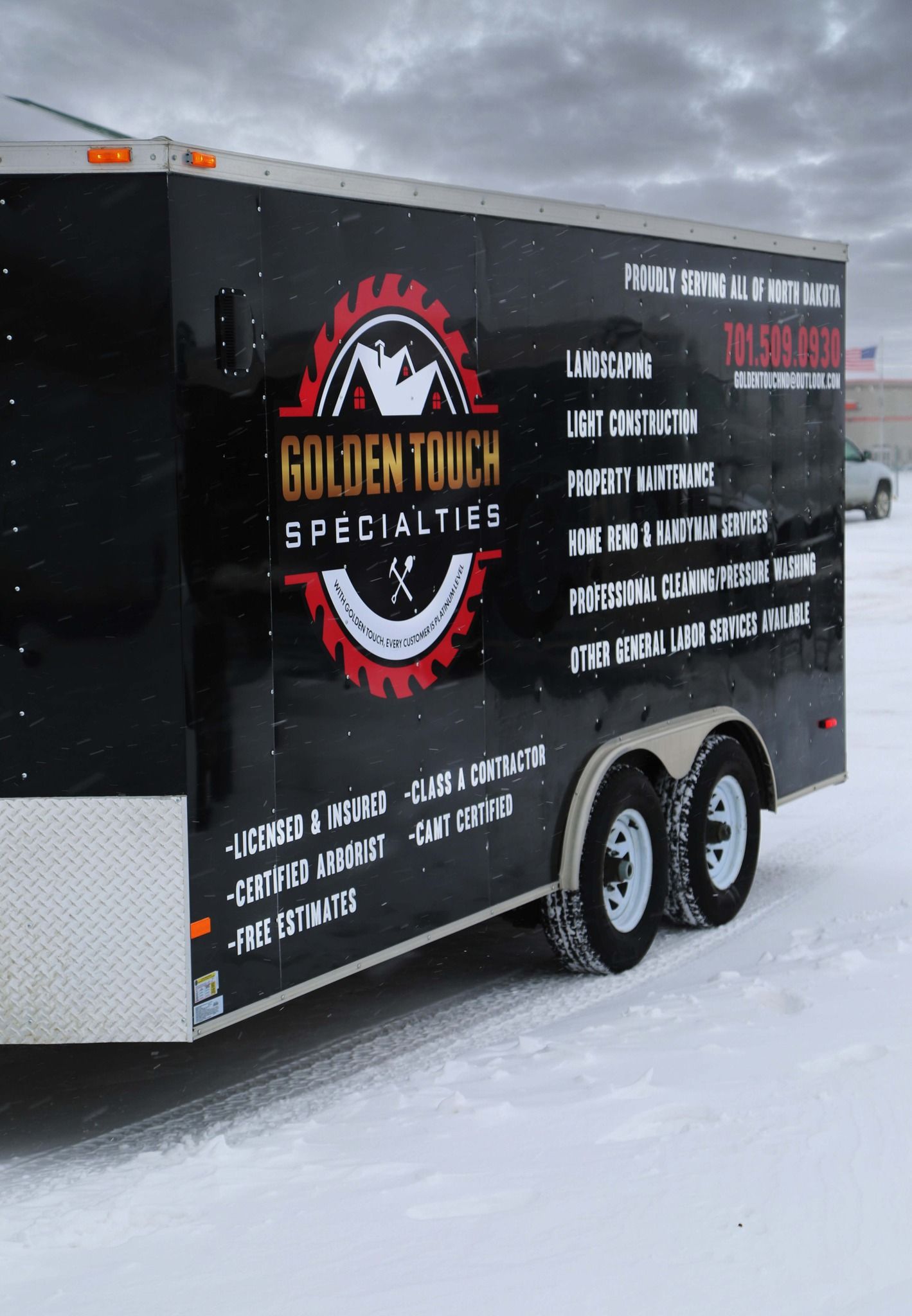 Black food trailer with red logo parked on snowy roadside in winter