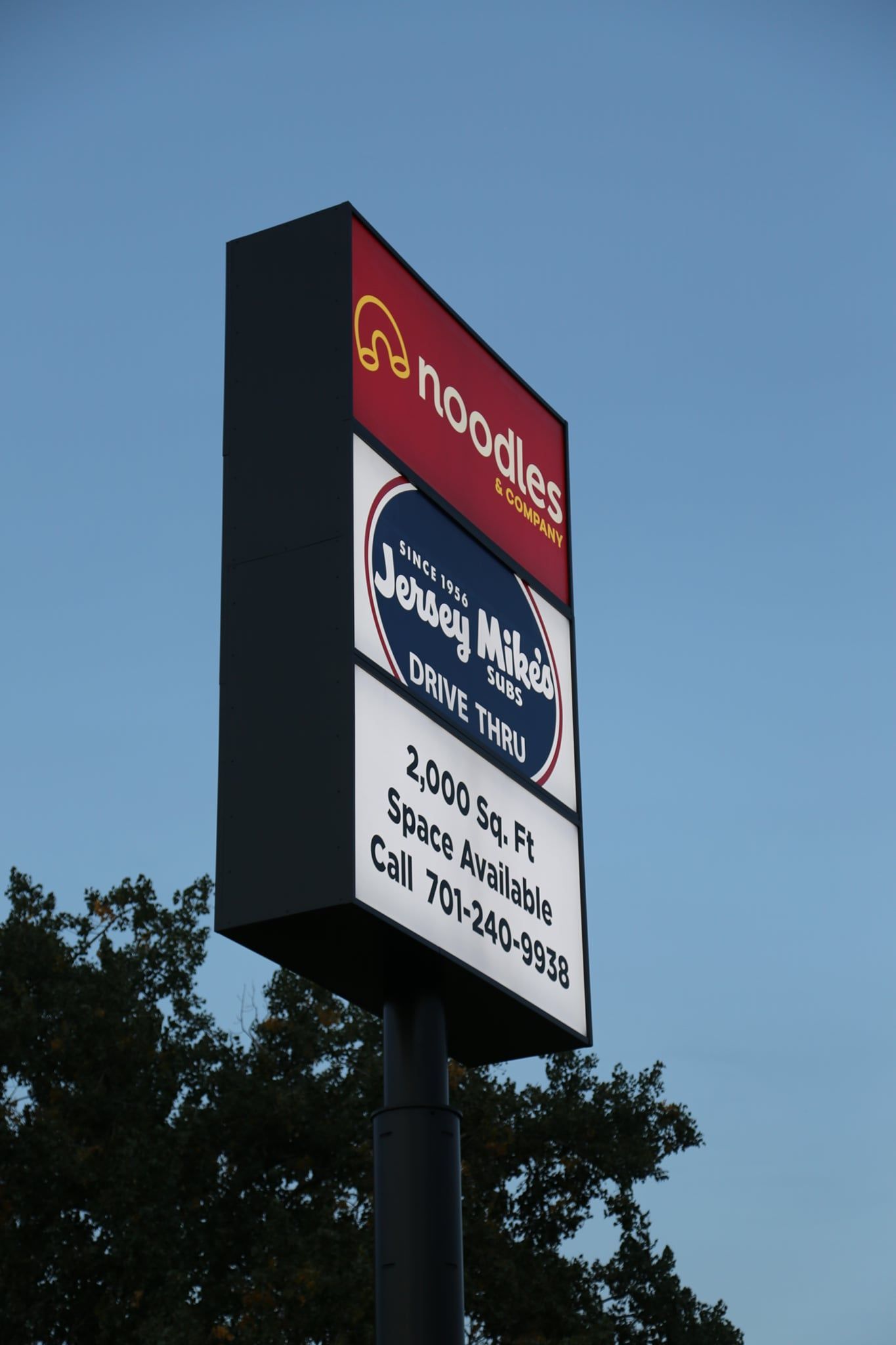 Tall roadside sign with a red top and white lower panels against a blue sky.