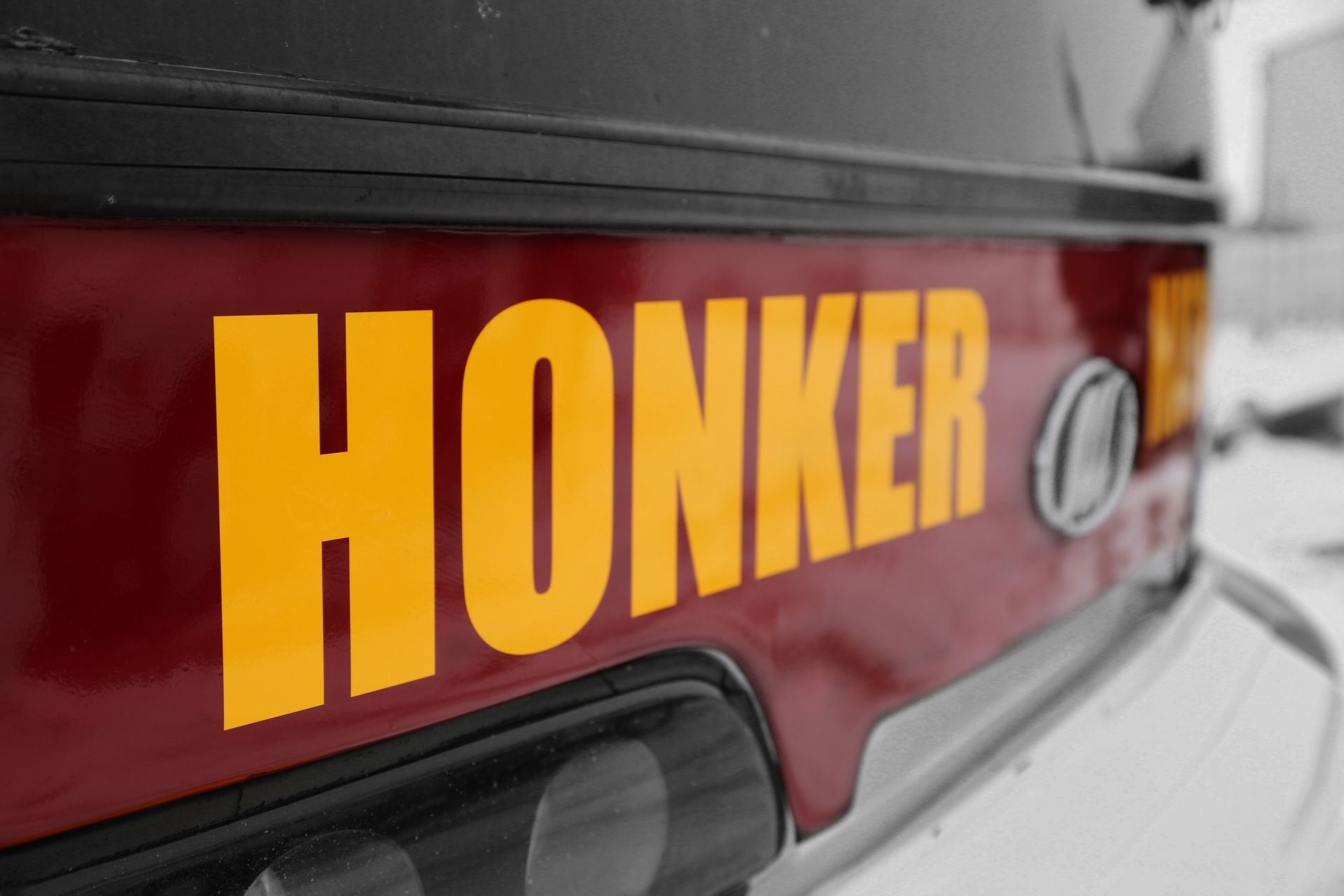 Close-up of a maroon vehicle with large yellow “HONKER” lettering on the rear panel