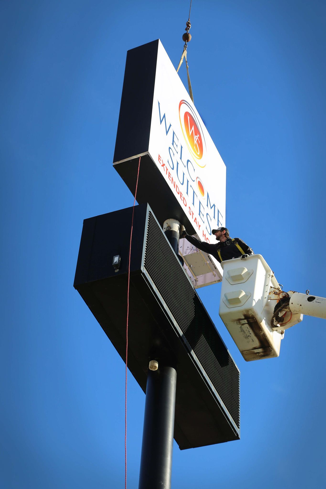 Tall illuminated roadside sign on a pole against a clear blue sky