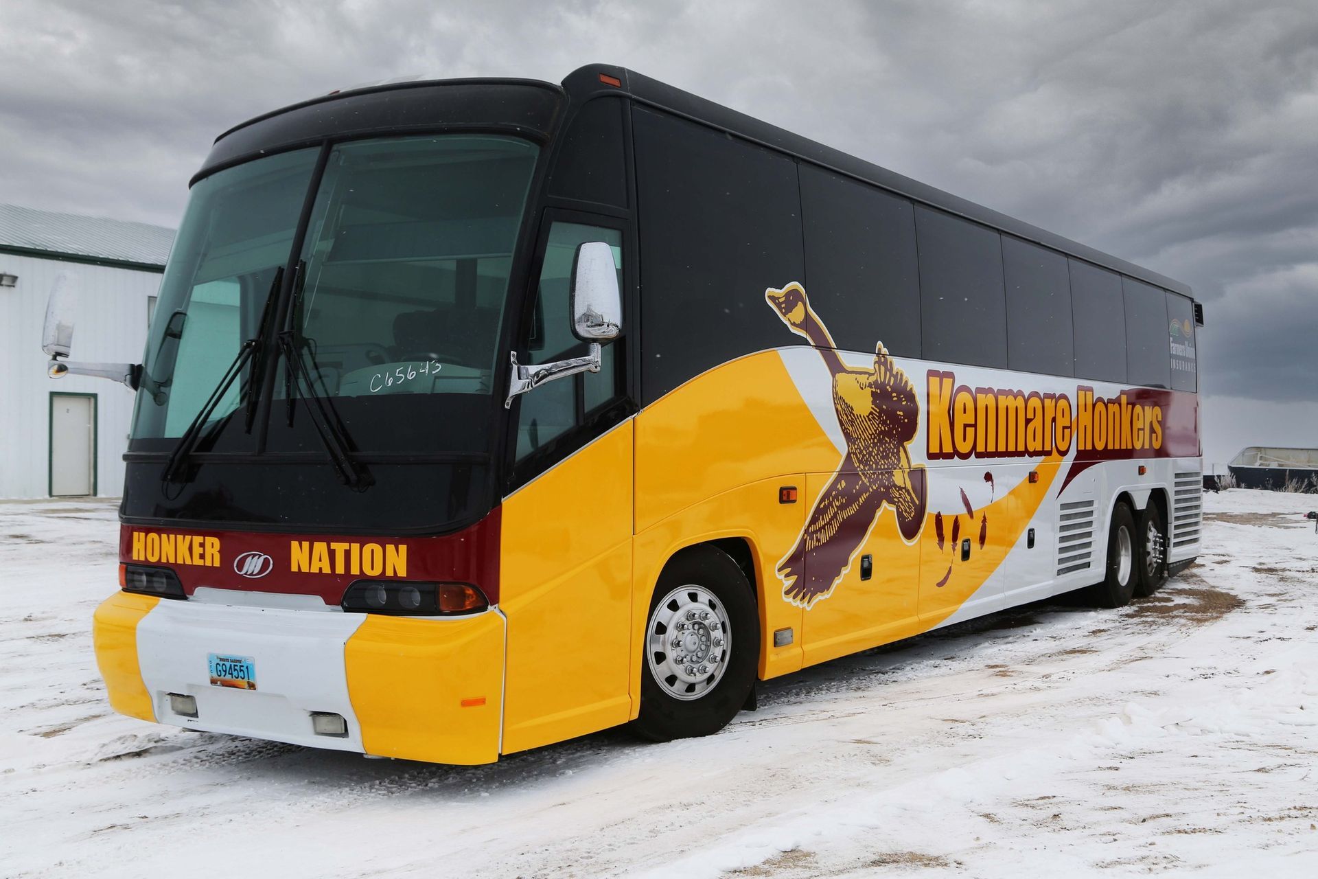 Yellow and black tour bus parked on snowy ground