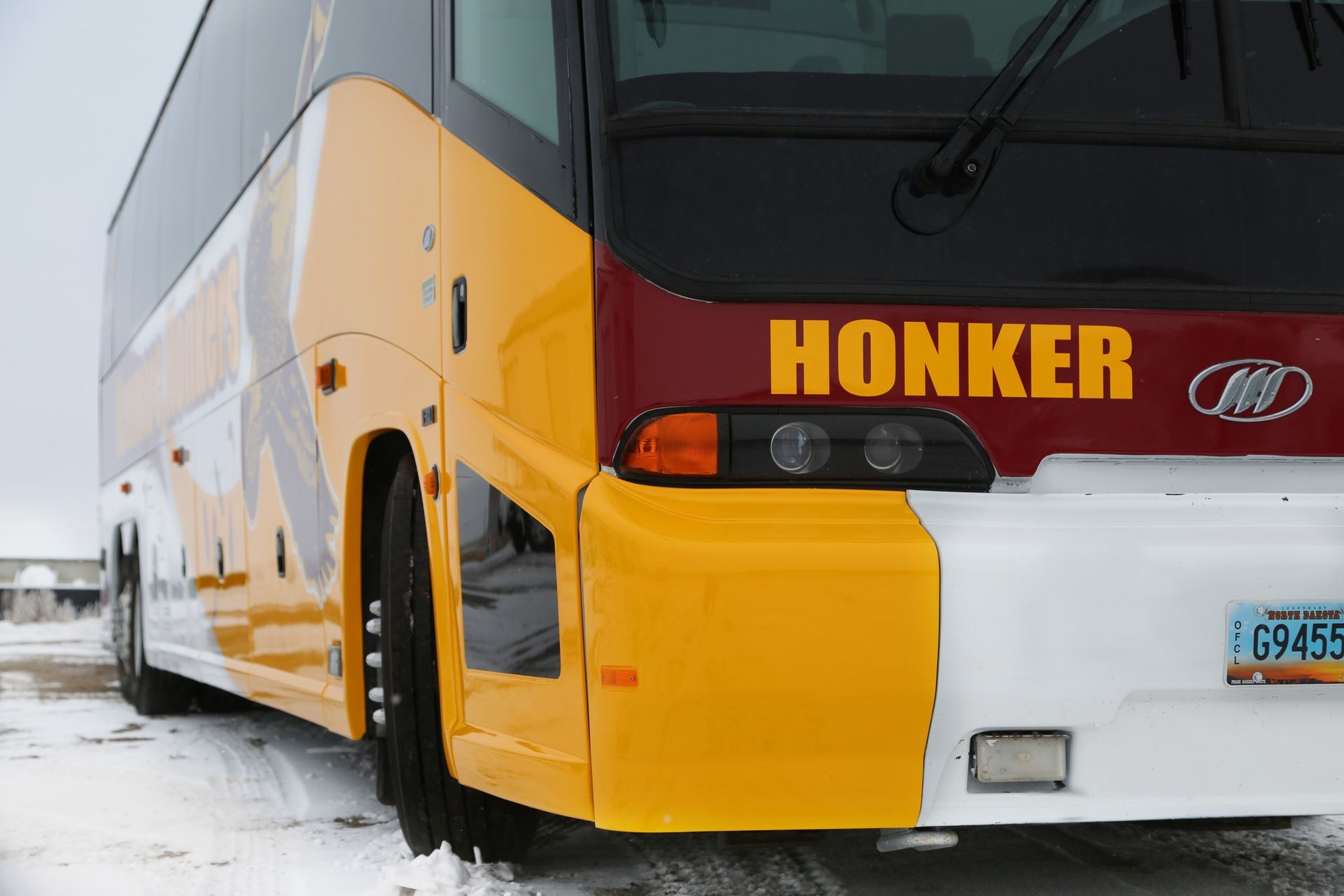 Yellow and red HONKER bus parked in snow, front-left view