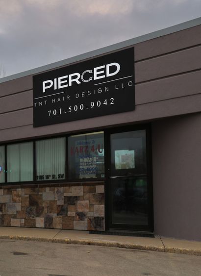 Storefront with a black “PIERCED” sign on a gray building exterior.