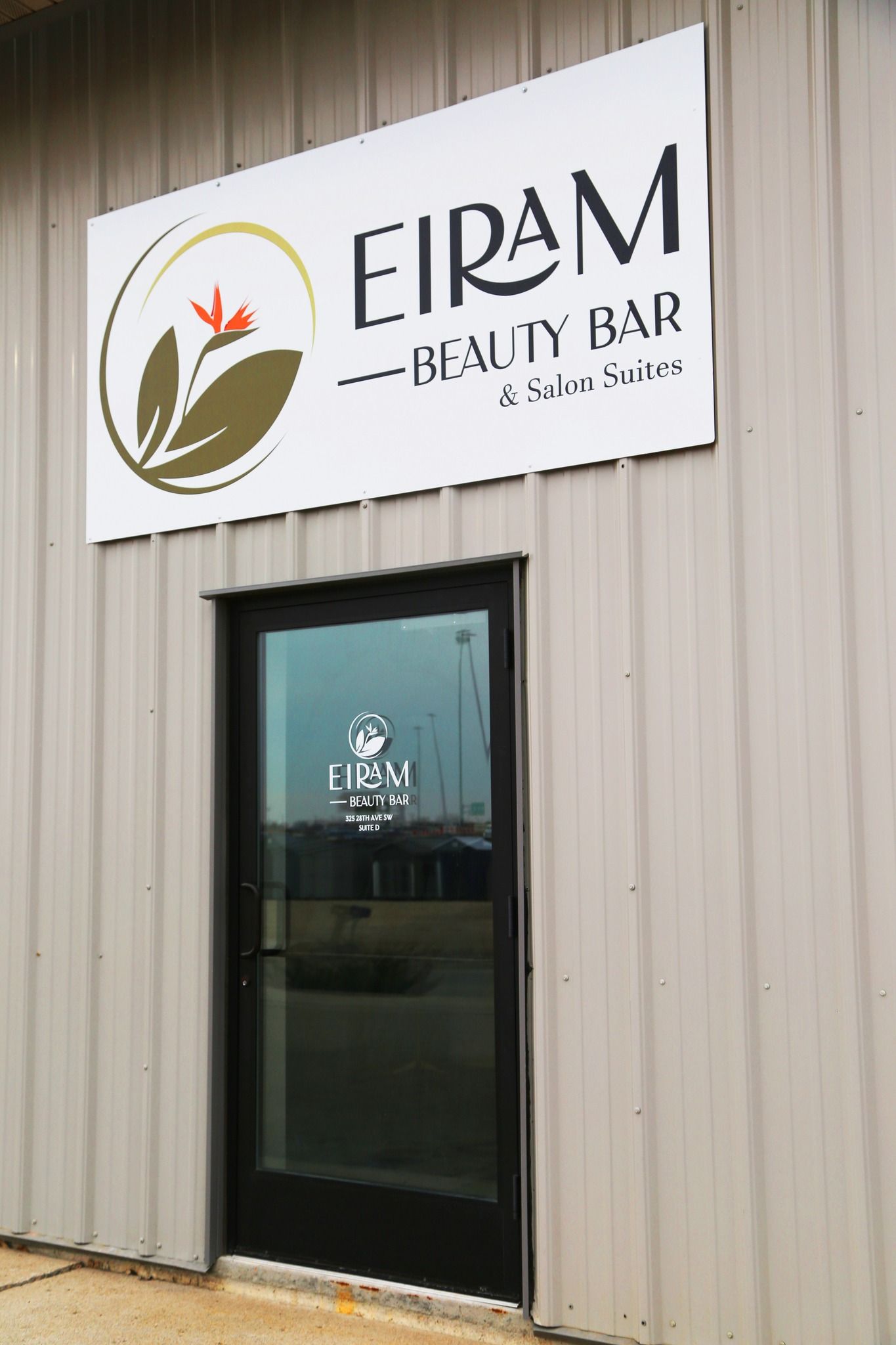 Storefront with a sign reading “EIRAM Beauty Bar” above a glass door on a metal building.