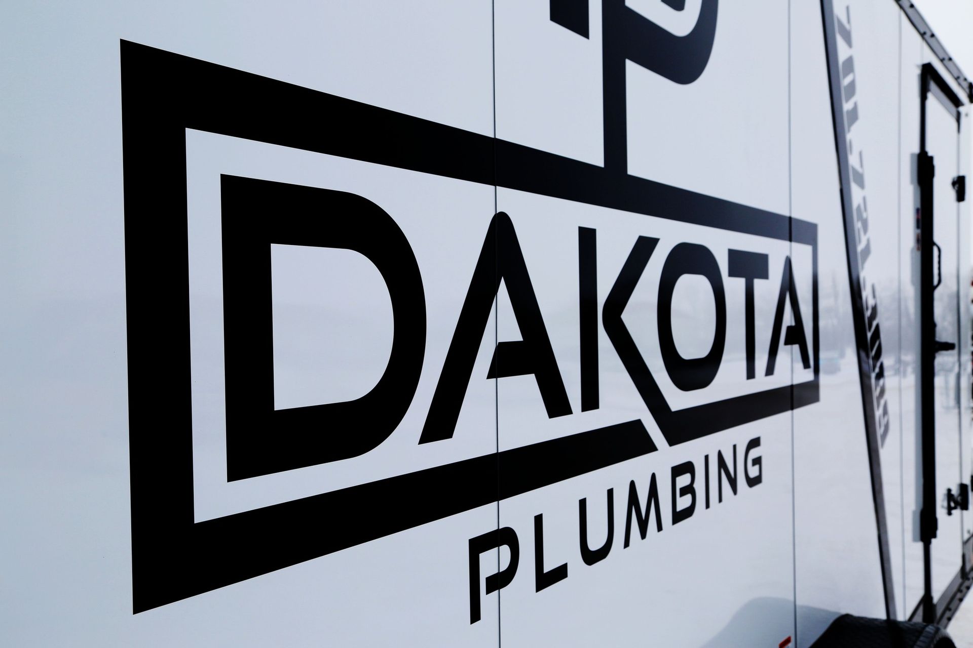 Dakota Plumbing logo in black on a white truck side panel
