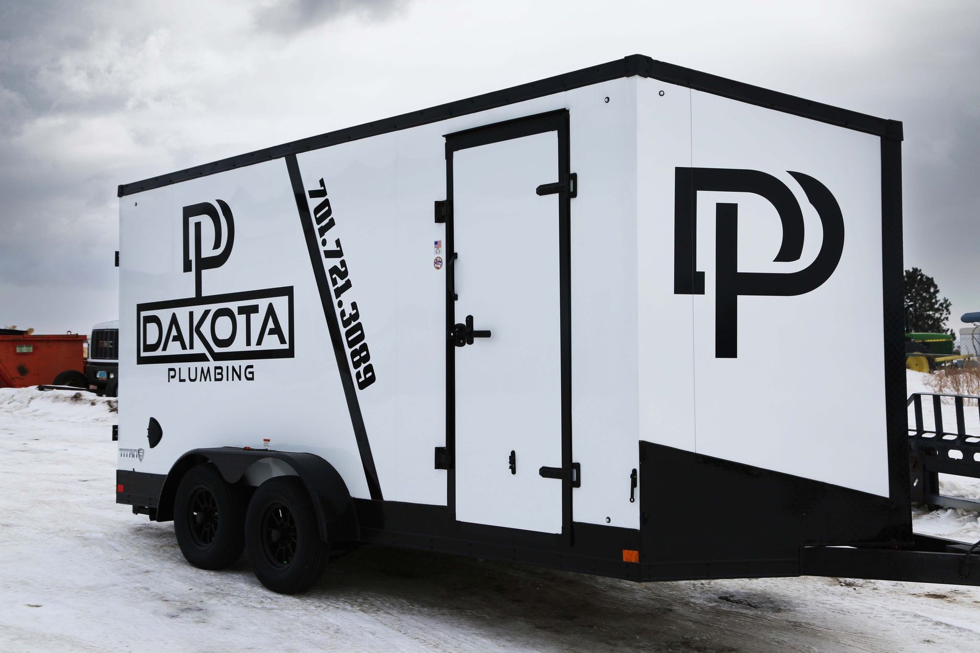 White Dakota trailer with black trim and logo, parked on snow-covered ground.
