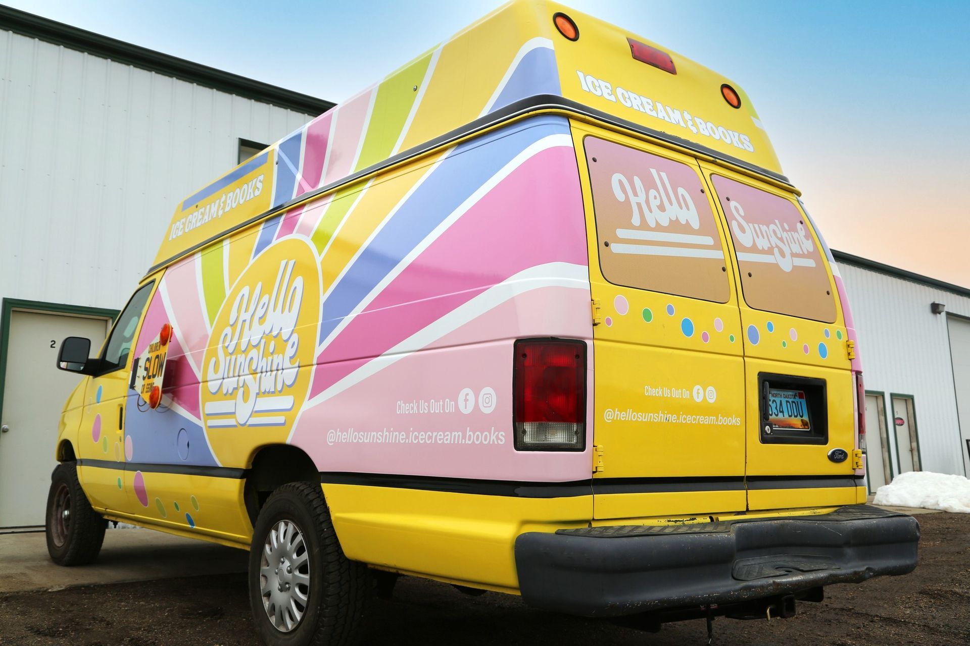 Colorful pink and yellow branded van parked beside a white building