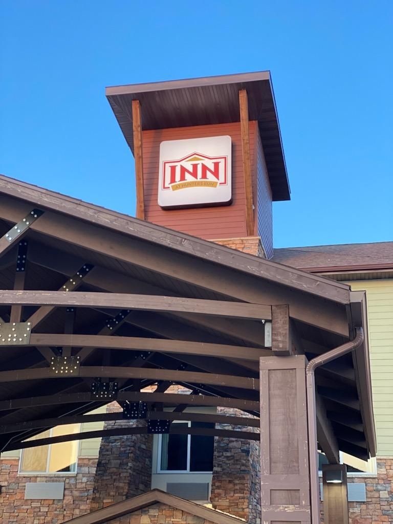 Inn sign on a brick building entrance under a wooden canopy against a blue sky