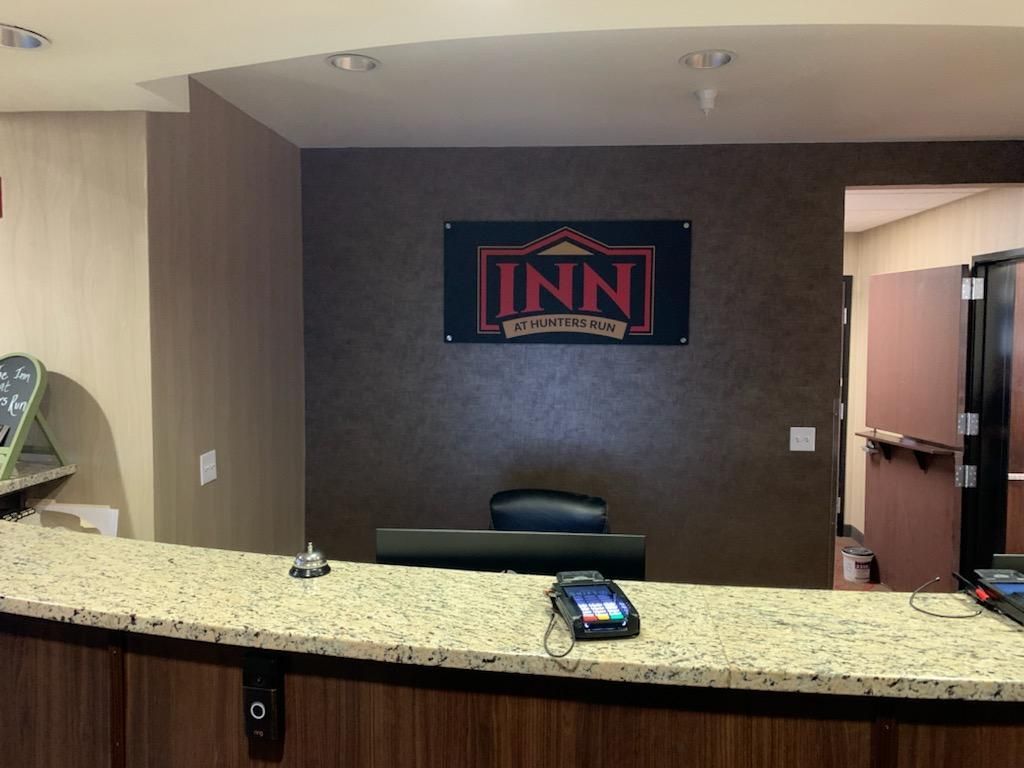 Hotel front desk with granite counter, black chair, and LINN sign on the back wall.