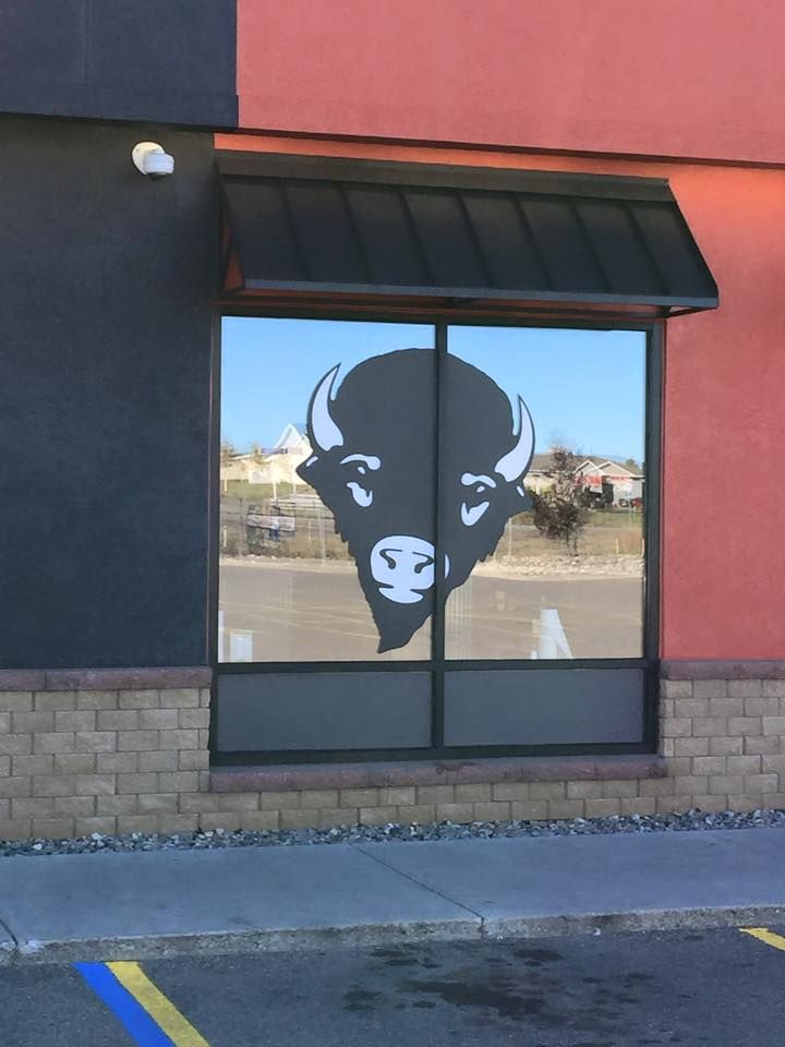 Bison logo on a storefront window with black awning and red-orange wall.