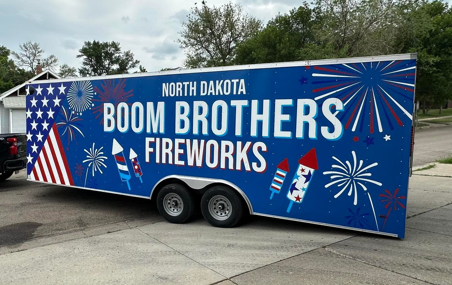 Boom Brothers Fireworks trailer with blue patriotic graphics and red, white, and blue fireworks display