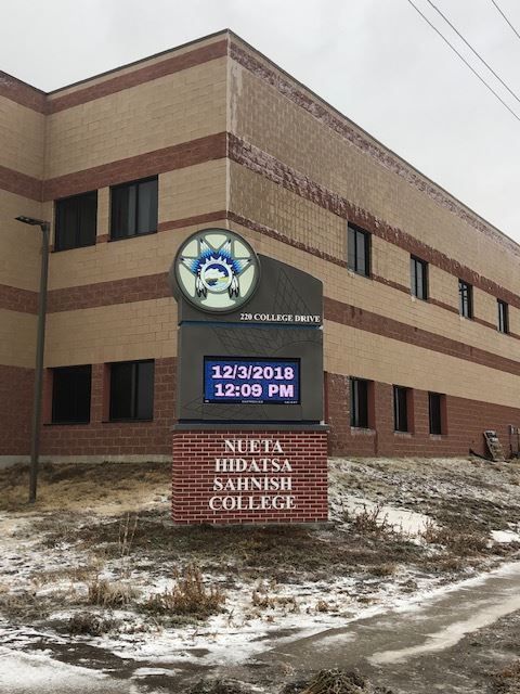 Northeast Hamilton School building with sign and digital clock in snowy weather