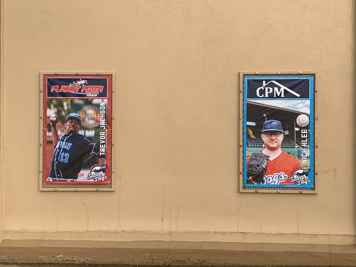 Two framed baseball player posters on a tan wall, one red-bordered and one blue-bordered.