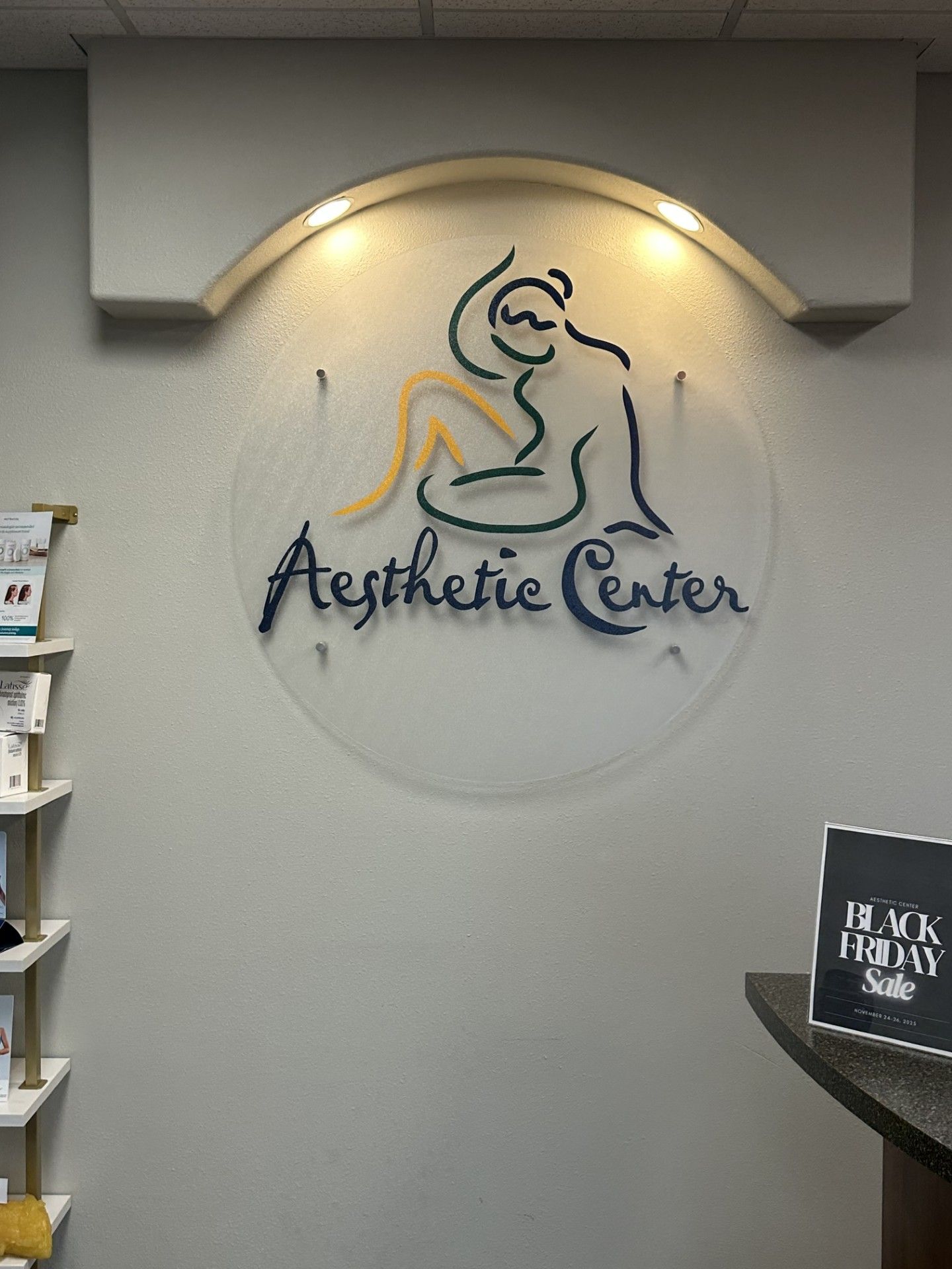 Aesthetic Center wall logo with a stylized figure and soft spotlight above a reception area