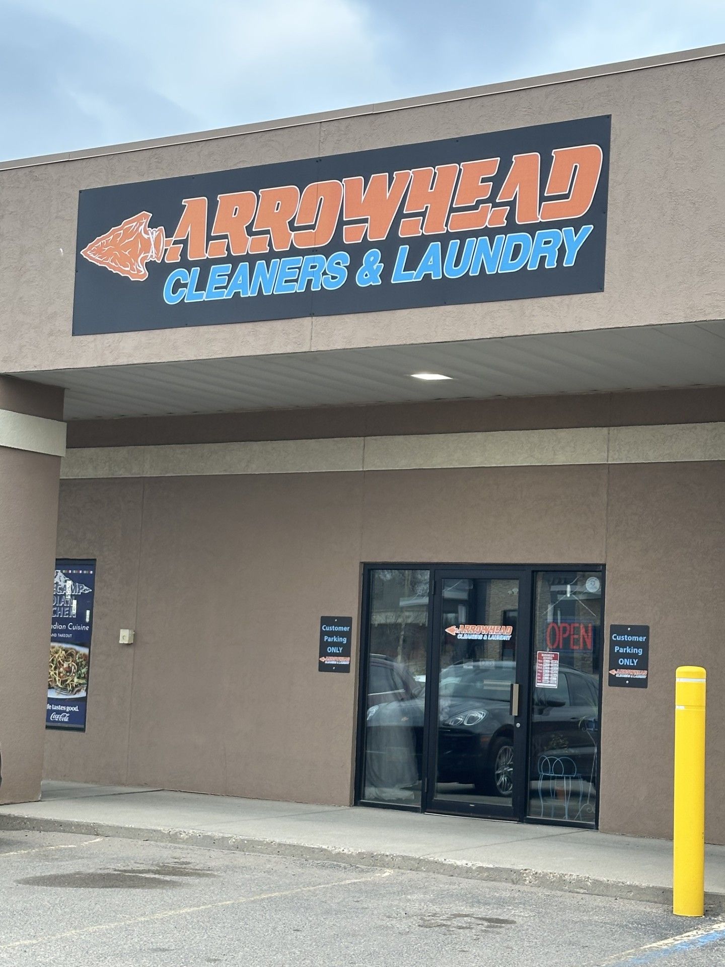 Storefront for Arrowhead Cleaners & Laundry with glass entrance and parking lot exterior.