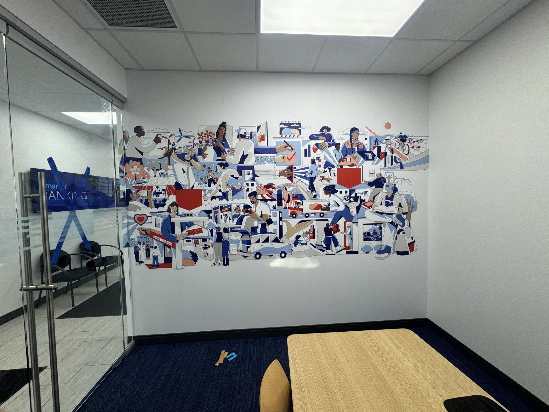 Empty room with blue carpet, wall collage of photos, and a wooden table in the foreground
