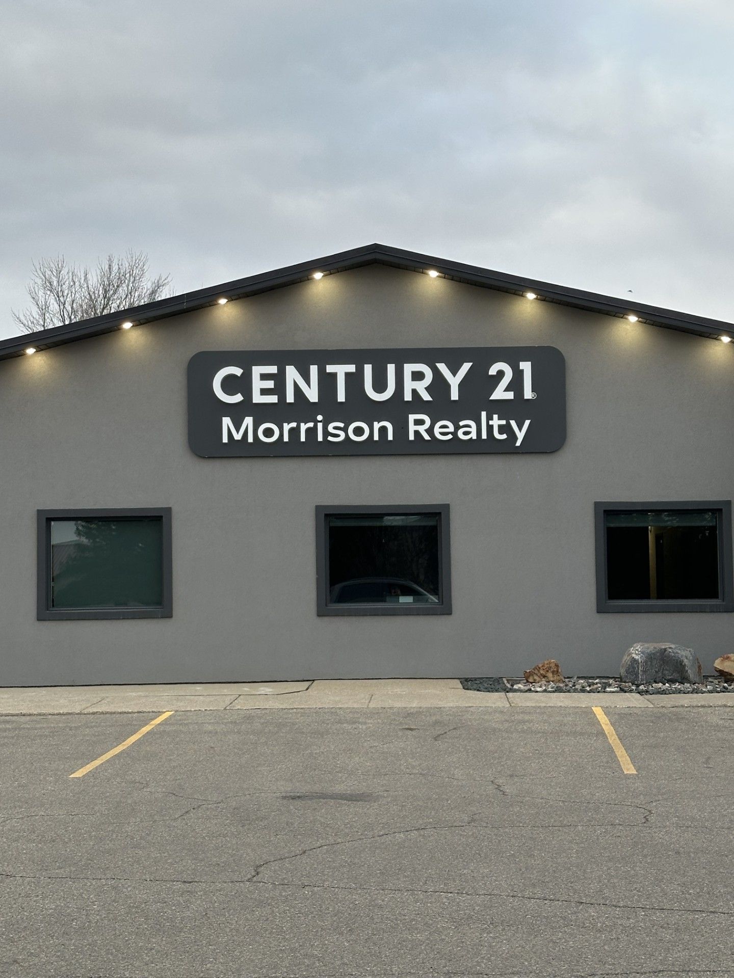 CENTURY 21 Morrison Realty storefront with gray facade, lit roofline, and parking spaces in front