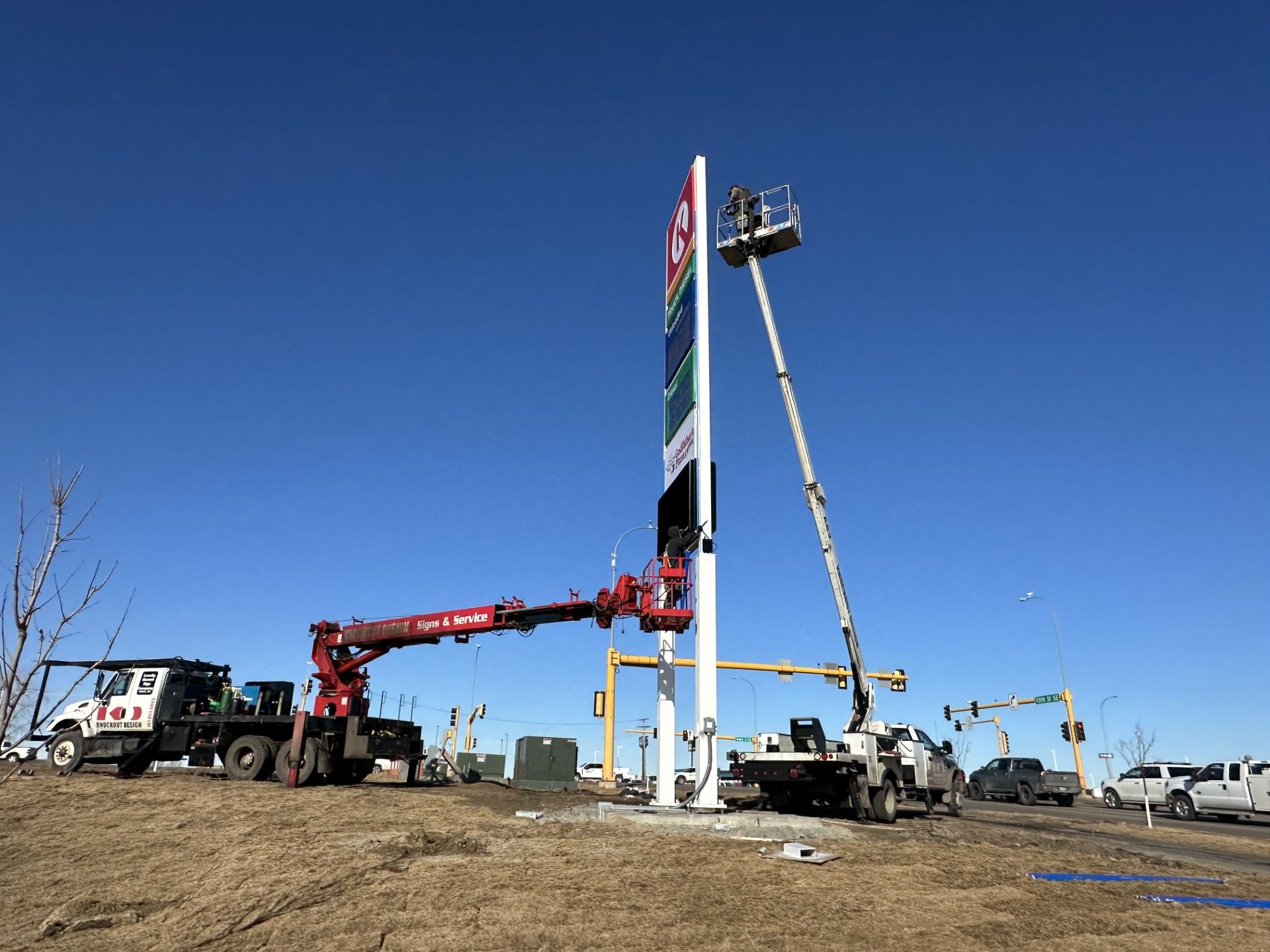 Crane lifting a tall sign on a construction site under a clear blue sky