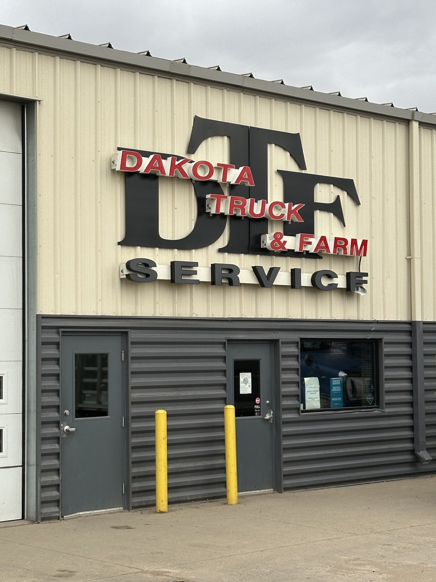 Dakota Truck & Trailer Service building exterior with large black and red sign above gray doors