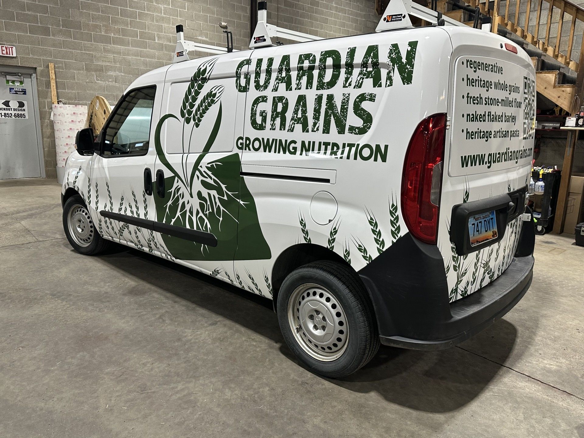 White Guardian Grains van with green farm graphics parked indoors at an industrial facility