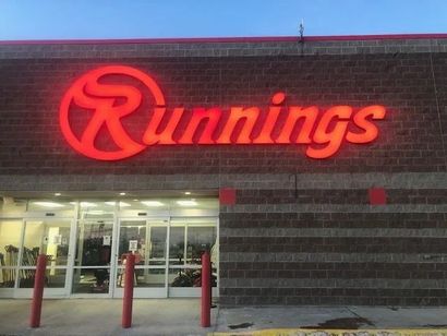 Runnings store storefront with bright red sign above glass entrance at dusk